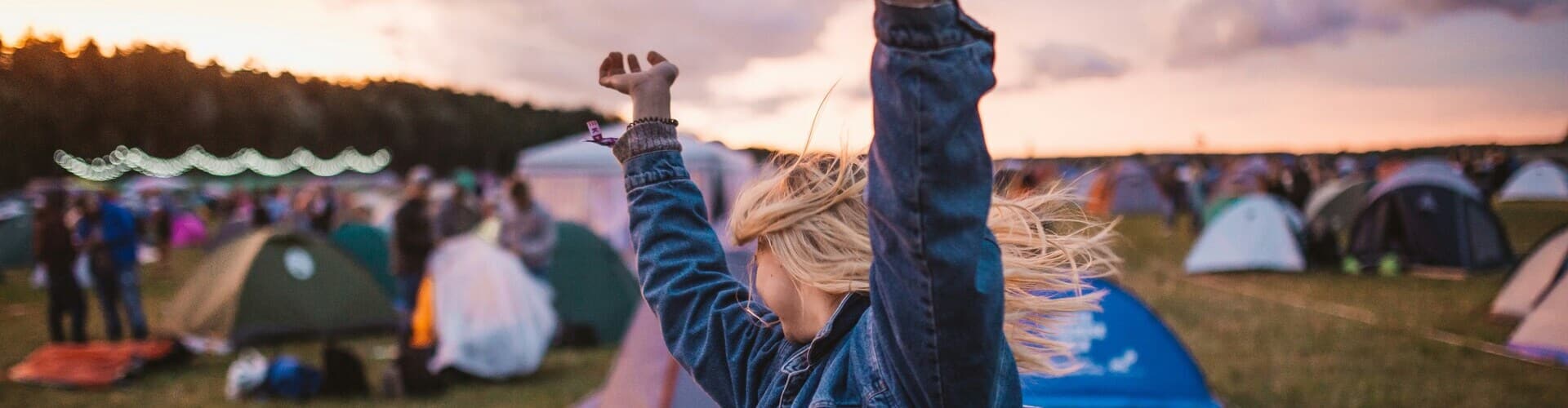 Woman dancing at festivals with tents set up all around her.