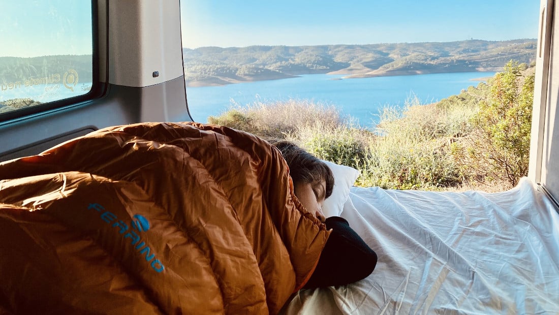 woman in a sleeping bag inside a camper van