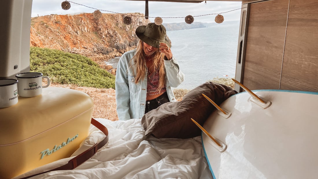 woman in the back of a camper van by the coast
