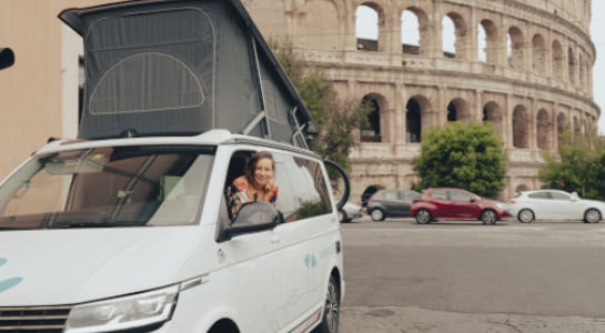woman inside a white campervan, colosseum in rome in the backround