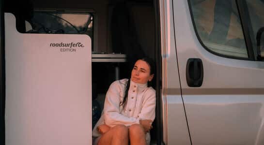 Woman sitting in door of boxvan.