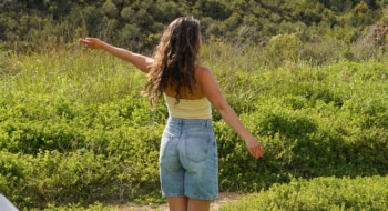 Woman standing in field stretching out her arms.