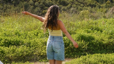 Woman standing in field stretching out her arms.