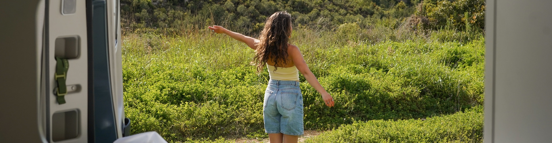 Woman standing in field stretching out her arms.