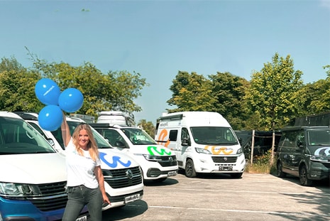 Woman stands with campervan and balloons