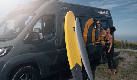 Woman using outdoor shower of a boxvan.