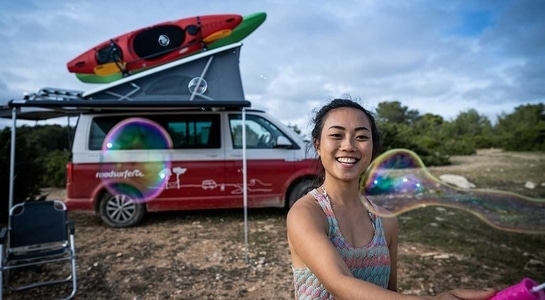 Woman doing some airbubbles with a red campervan behind her