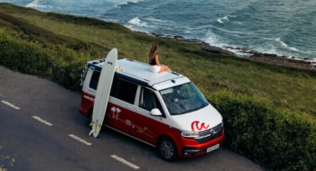 Women sitting on a campervan with a surfboard