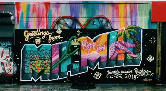 Colorful mural in Wynwood, Miami, reading “Greetings from Miami,” surrounded by vibrant graffiti art.