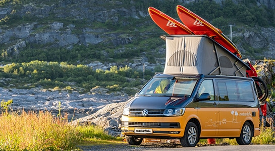 yellow camper van with stand up paddle boards on the top