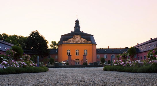 Yellow castle in Mönchengladbach with flowerbeds in the frontyard.