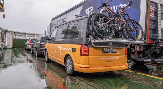 yellow campervan with bike rack standing on a ferry