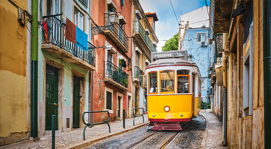 Yellow tram in Lisboa driving through a narrow alleyway