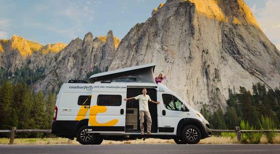 RV parked beneath towering granite cliffs in Yosemite National Park in California, a top destination for hiking and climbing.