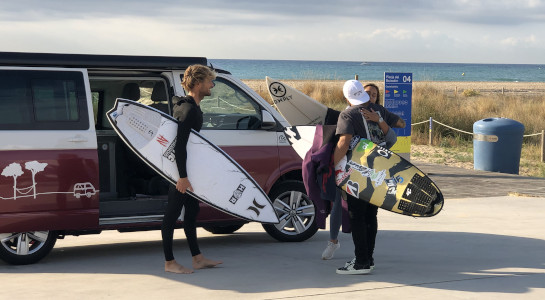 three surfers hugging by the sea van in the back