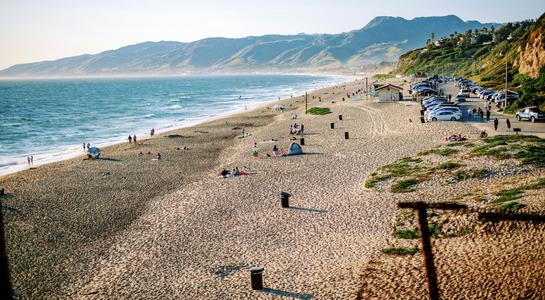 People relaxing along the wide sandy shoreline at Zuma Beach, one of the most scenic beaches in LA.